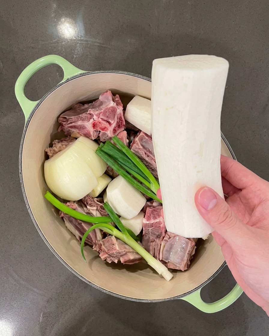 肉と香味野菜の入った鍋に、大きめに切った大根を入れている様子。