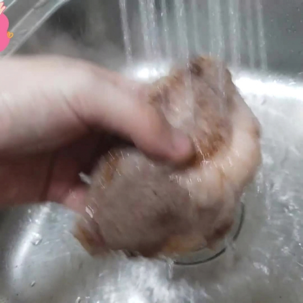 下茹でした牛カルビを、シンクで流水に当てて洗っている様子。