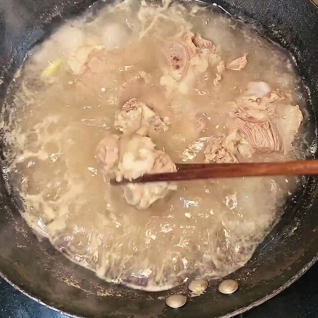 沸騰したお湯から菜箸で茹でた牛スペアリブを取り出している様子。
