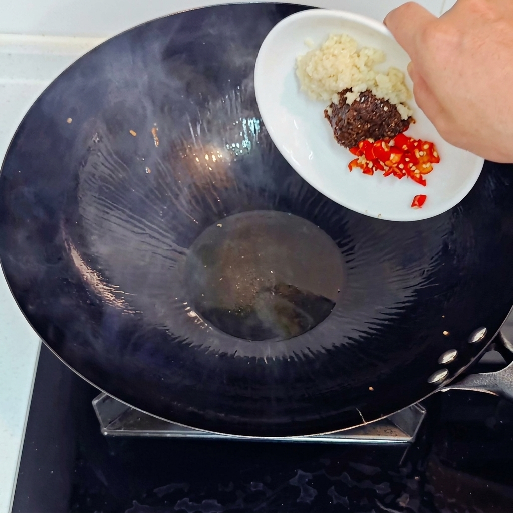 にんにく、唐辛子、味噌を鍋に入れて炒める様子。