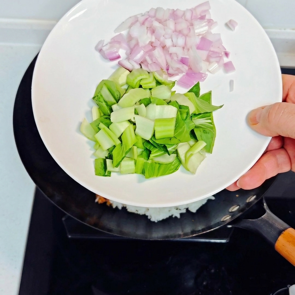 玉ねぎとチンゲン菜を鍋に加える様子。