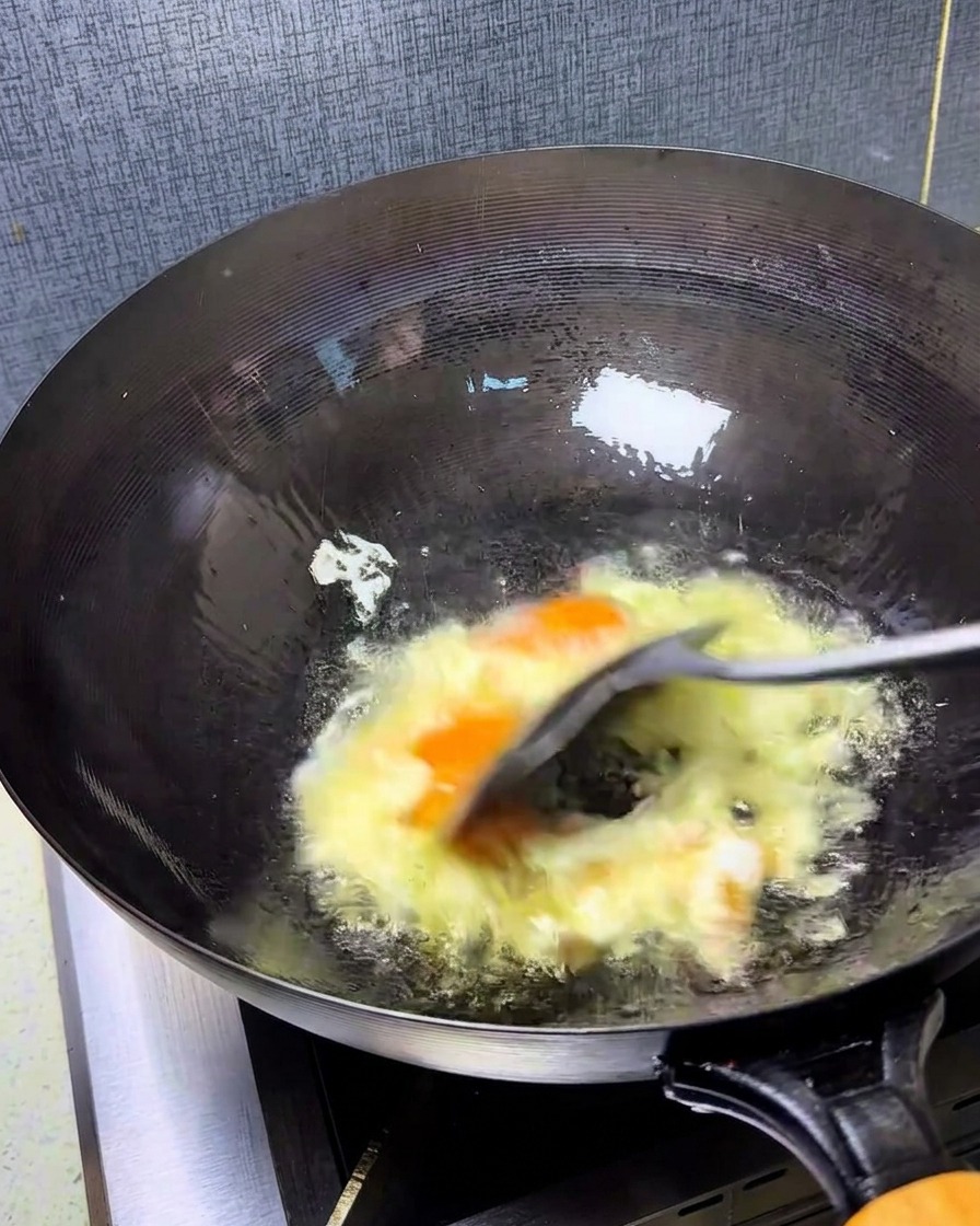 強火で手早く卵を混ぜ、ふんわりとした黄金色の炒り卵を作る様子。