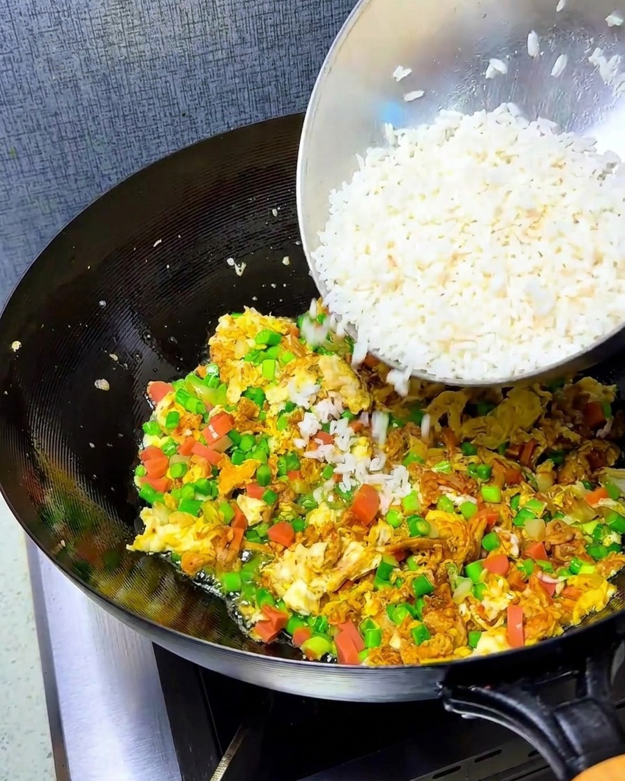 炒めた具材の中に、ほぐしたご飯を加える様子。