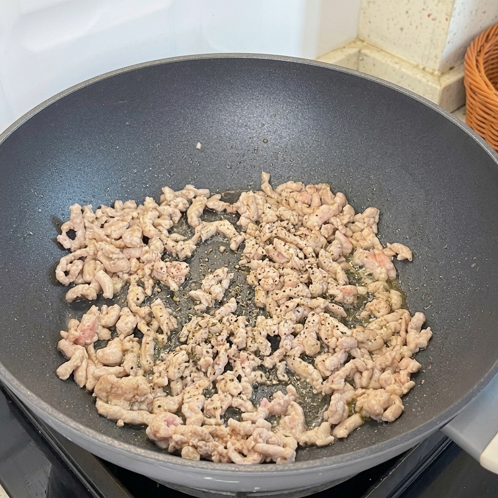 こんがり焼けた豚ひき肉に黒こしょうをふりかけている様子。