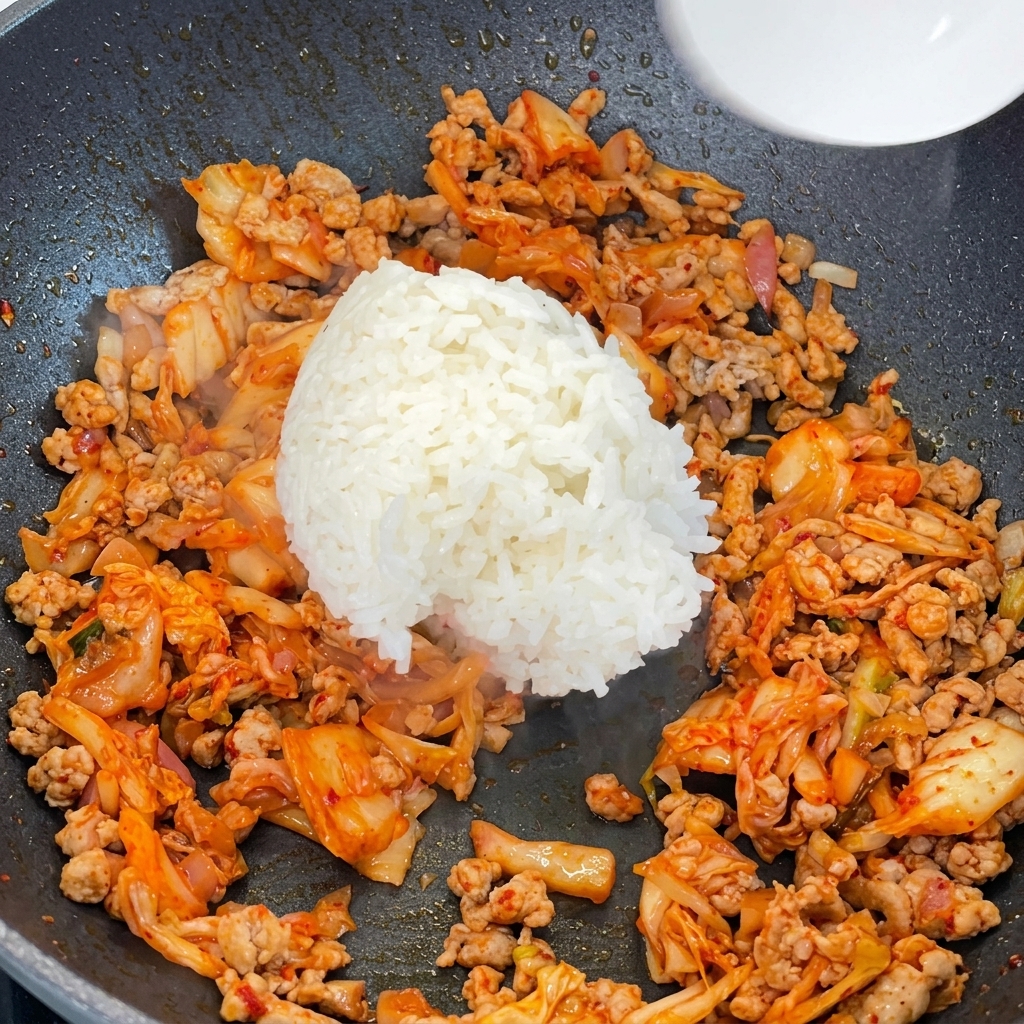 豚キムチを炒めたフライパンに白ご飯を加えている様子。