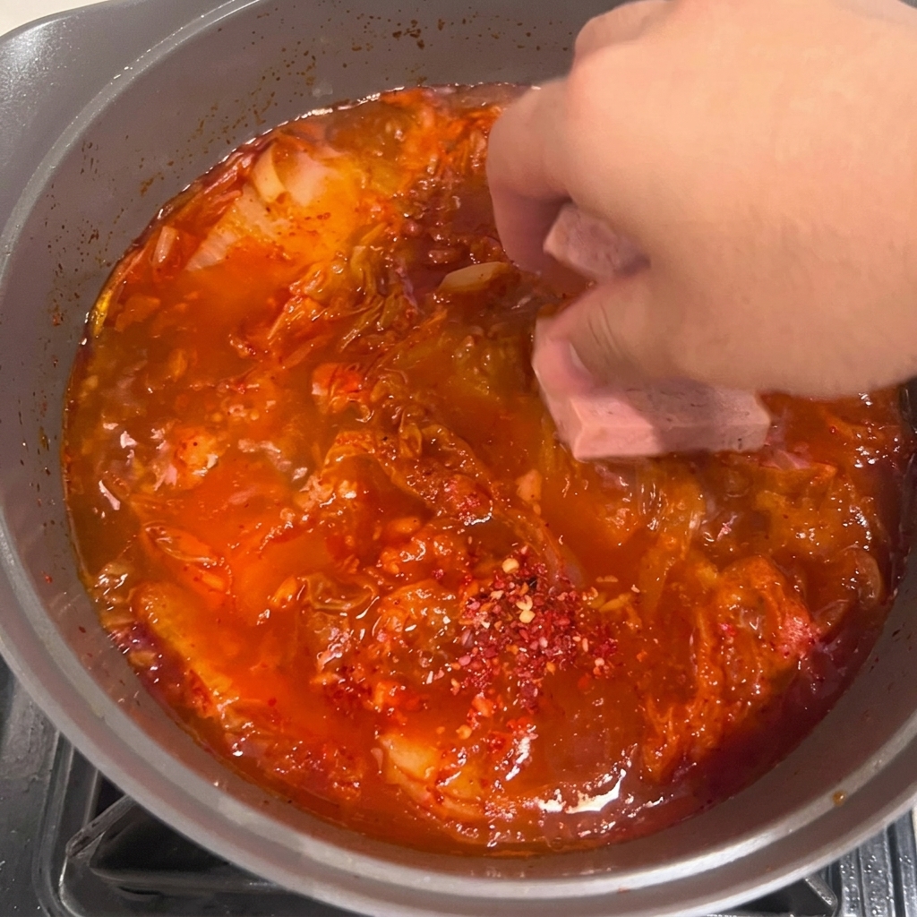 煮立つスープの中に豆腐をそっと入れている様子。