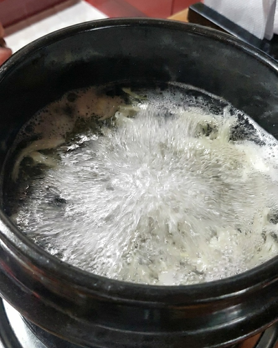 ぐつぐつ煮え立つ出汁に生のむきえびを加えている様子。
