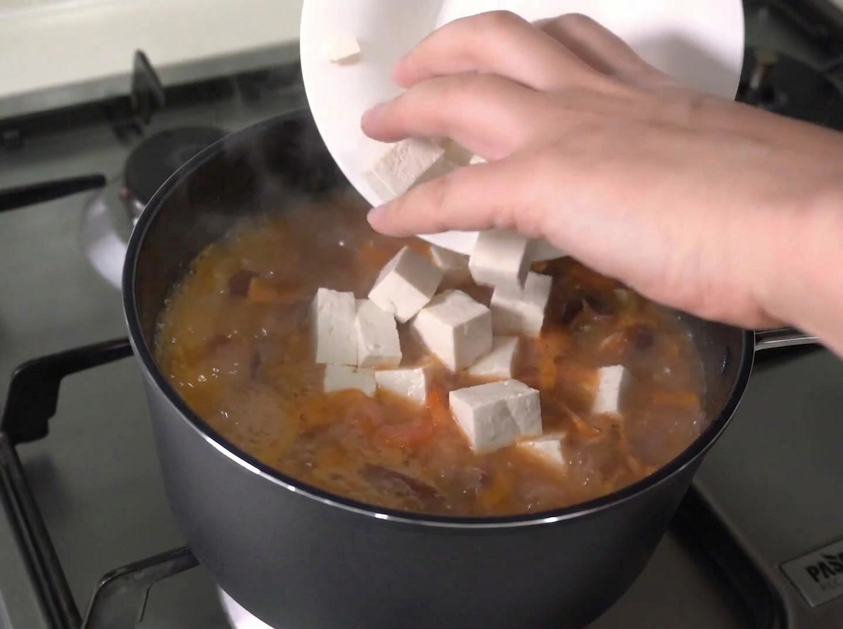切った豆腐を沸騰している鍋に入れている様子。