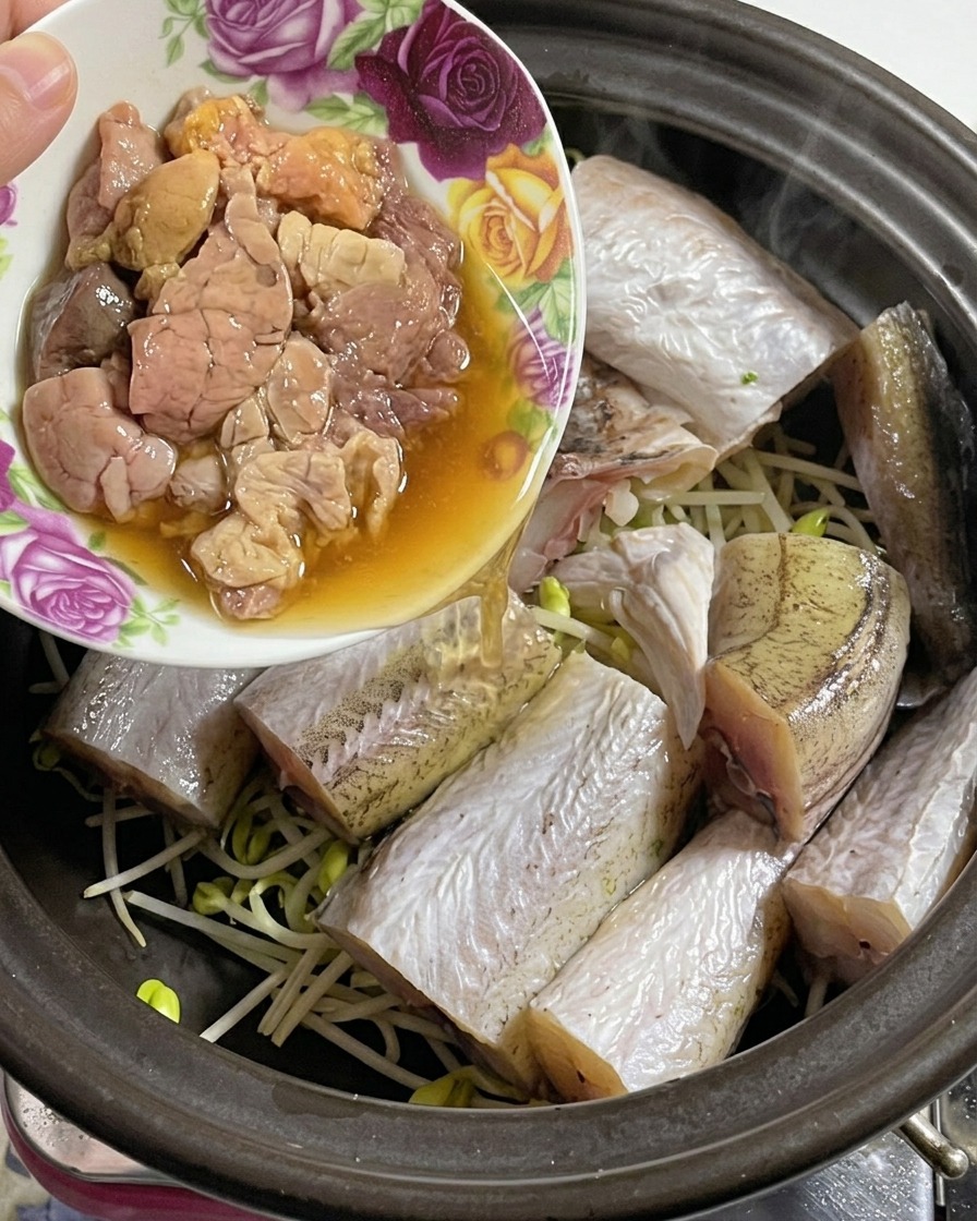 小花柄のボウルから、魚ともやしが入った土鍋に新鮮で繊細なタラコを入れている様子。