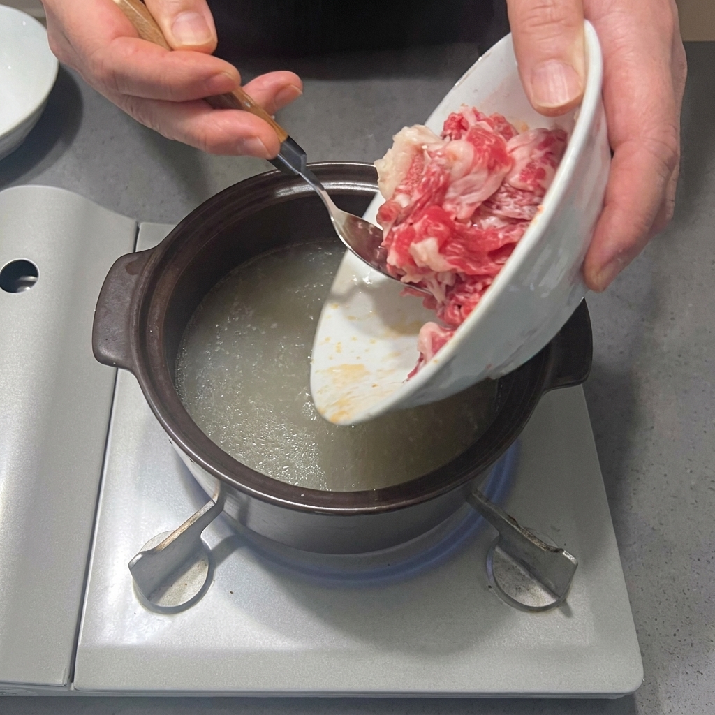だしスープに牛バラ肉のスライスを投入する様子。