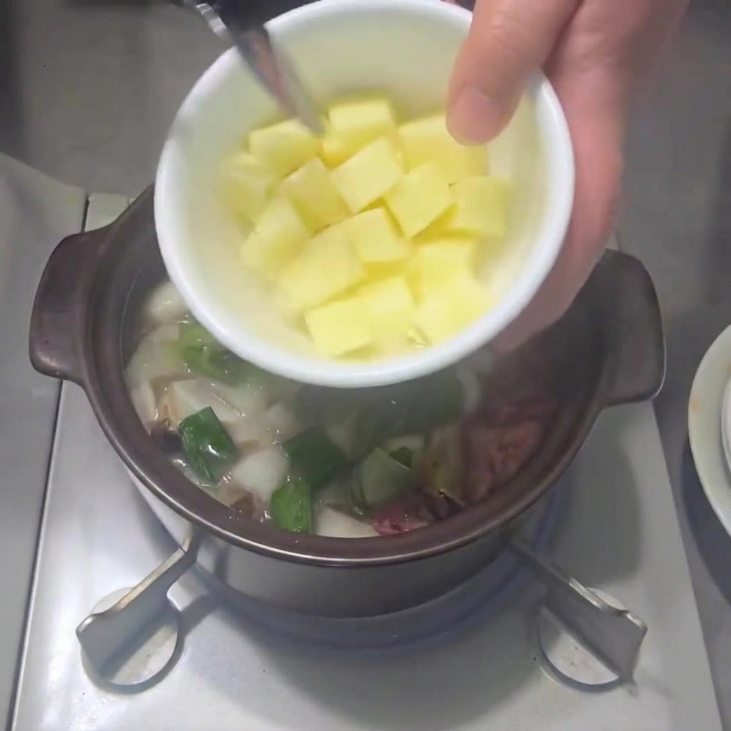 他の野菜が入った鍋にジャガイモを加える様子。