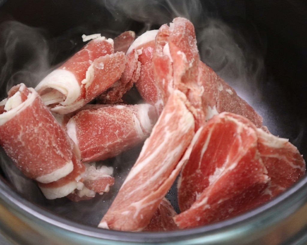 熱した石鍋の中で、脂が溶け出して焼けている牛バラ肉。