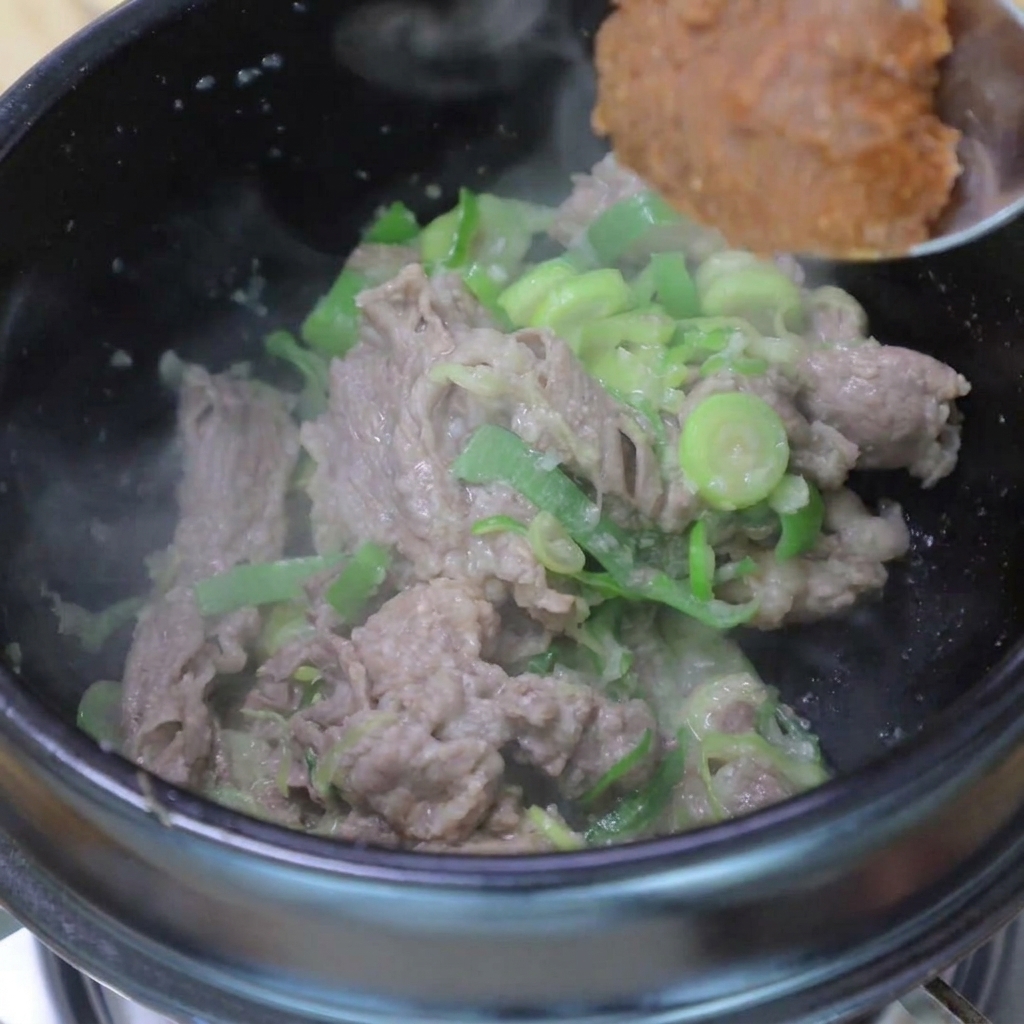 炒めた肉とねぎに、テンジャンとコチュジャンを加えている様子。