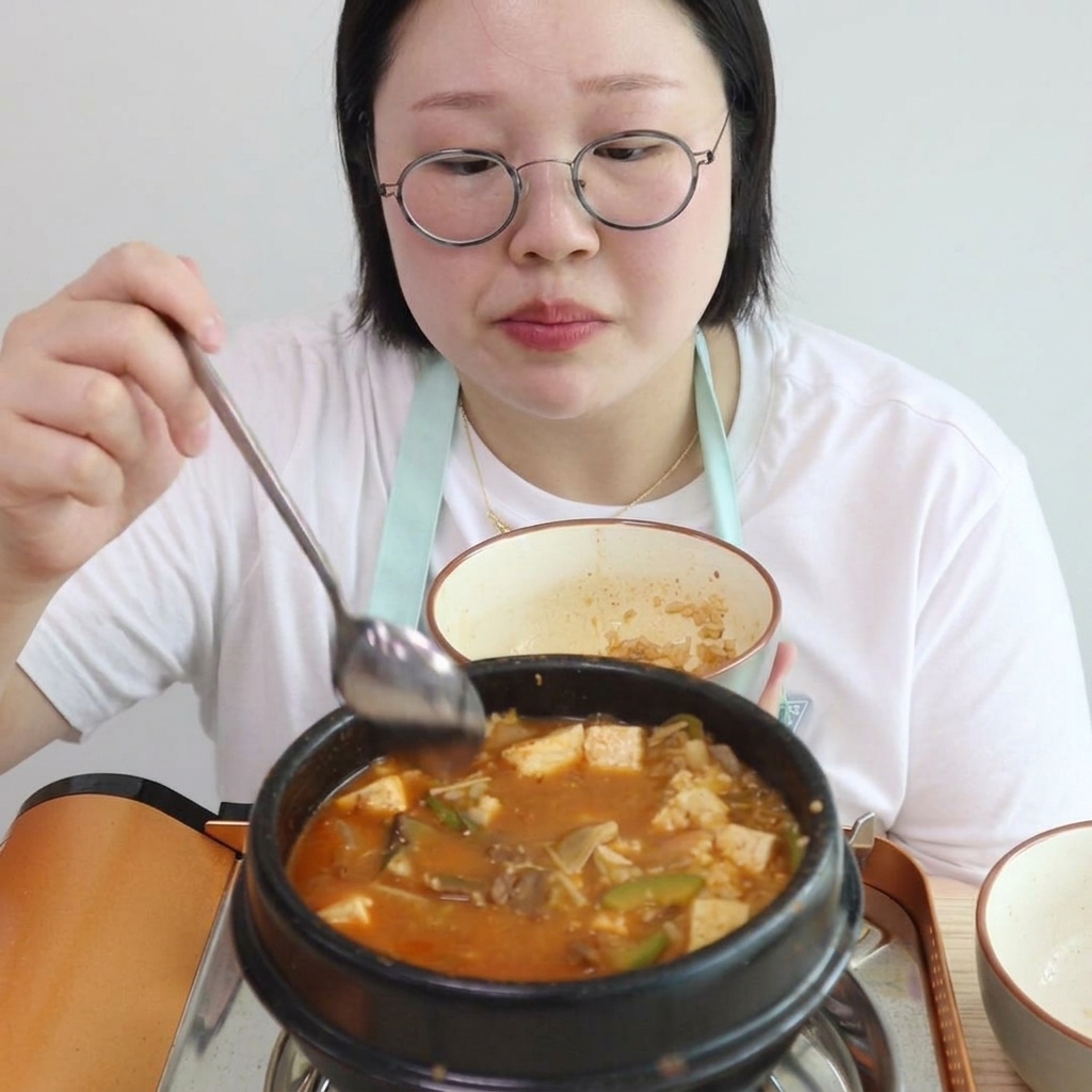 煮立っているチゲに白ご飯を混ぜ入れている様子。