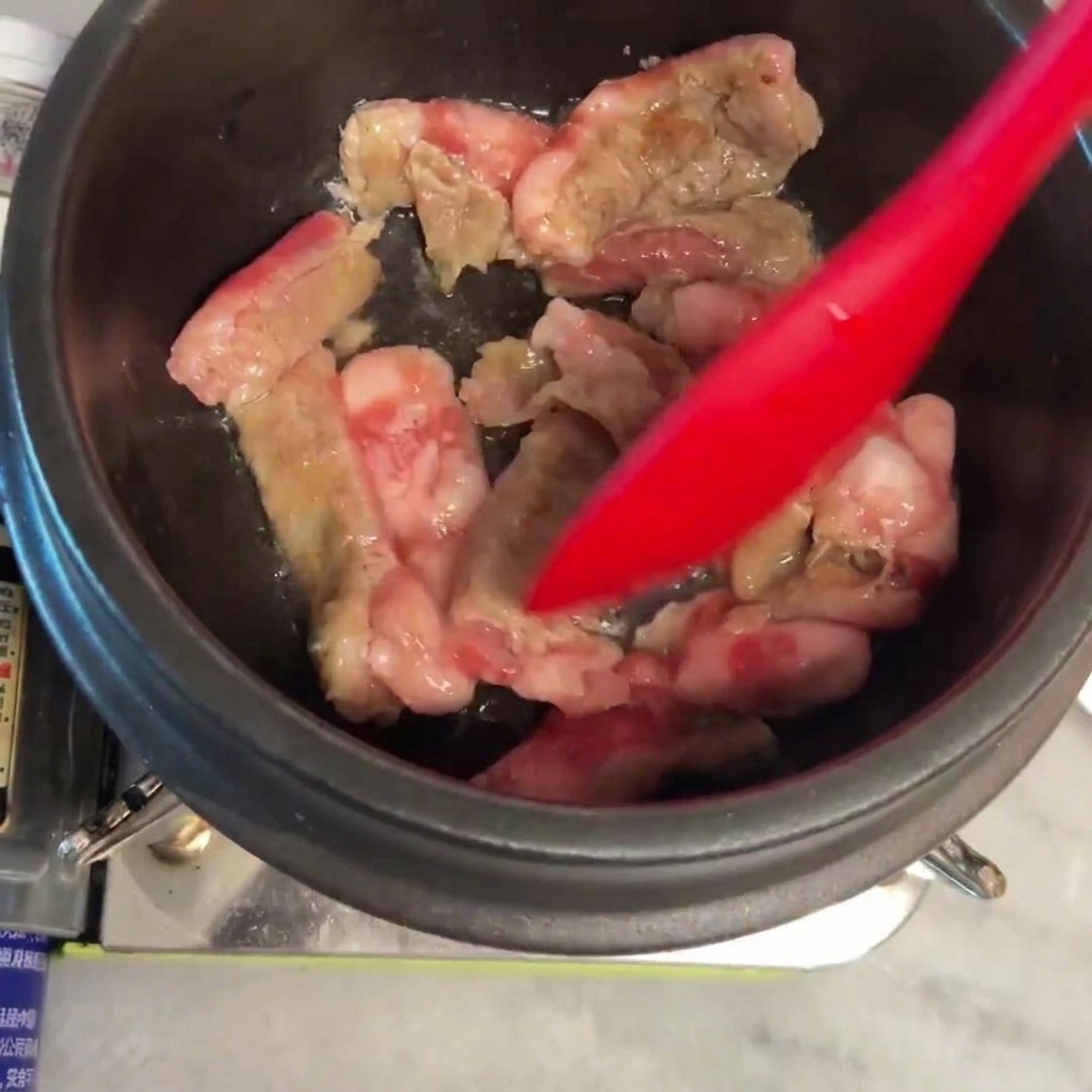 鍋の中で牛肉をヘラで炒め、焼き色がついてきた様子。