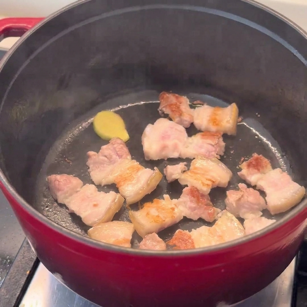 赤い鍋の中でこんがりと炒められた豚バラ肉。