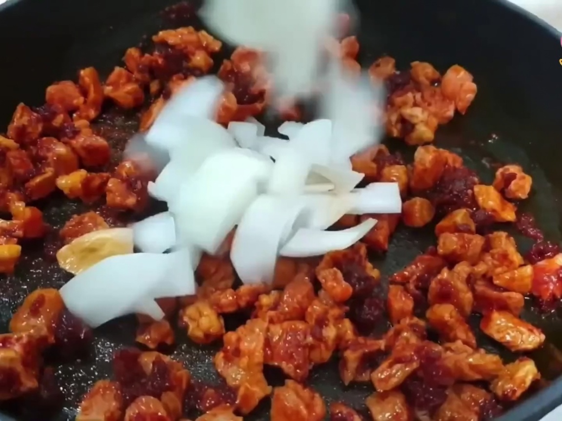 豚肉に玉ねぎ、長ねぎ、にんにくを加えて炒めている様子。