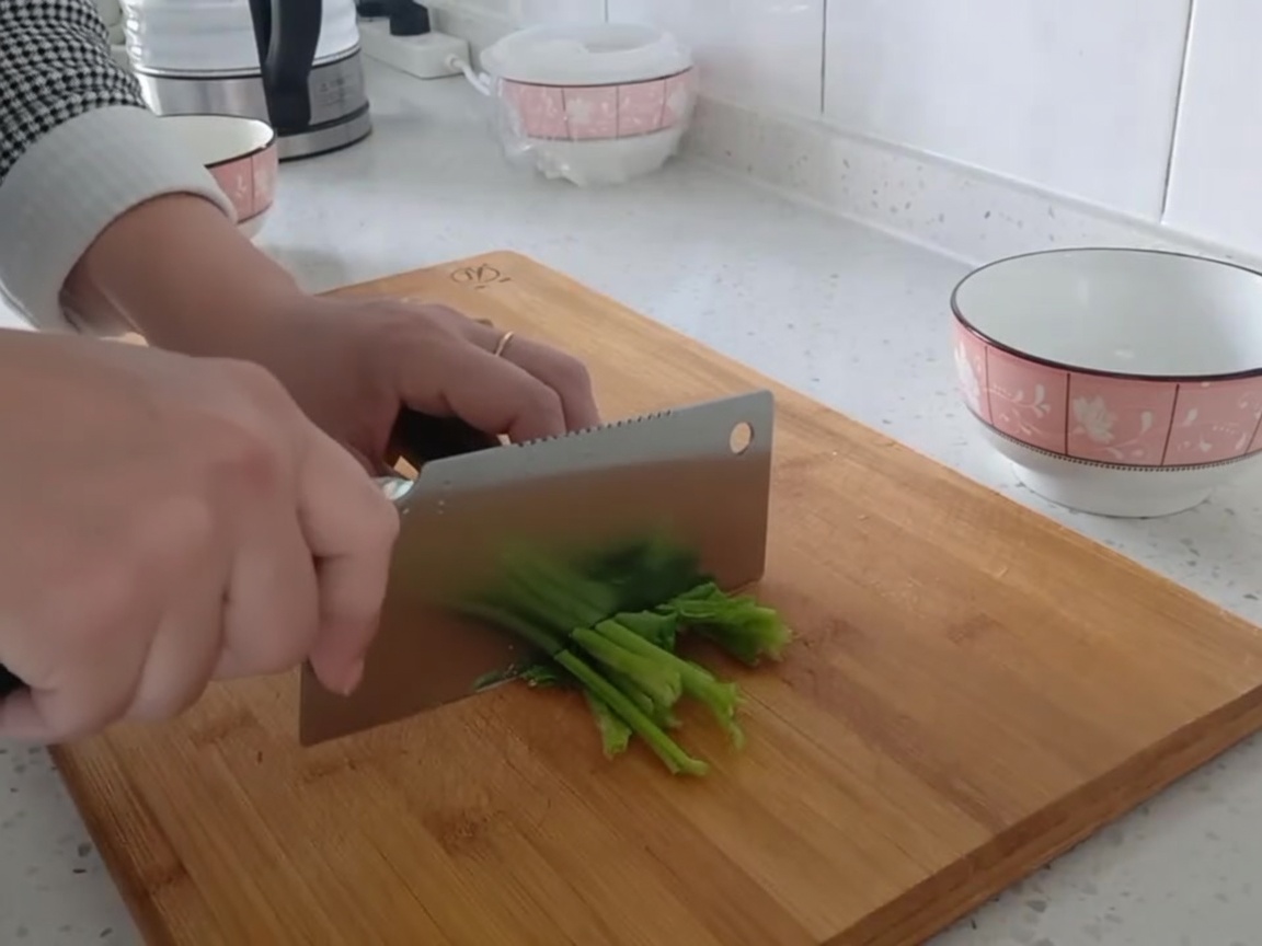 ほうれん草をまな板の上で食べやすい大きさに切っている様子