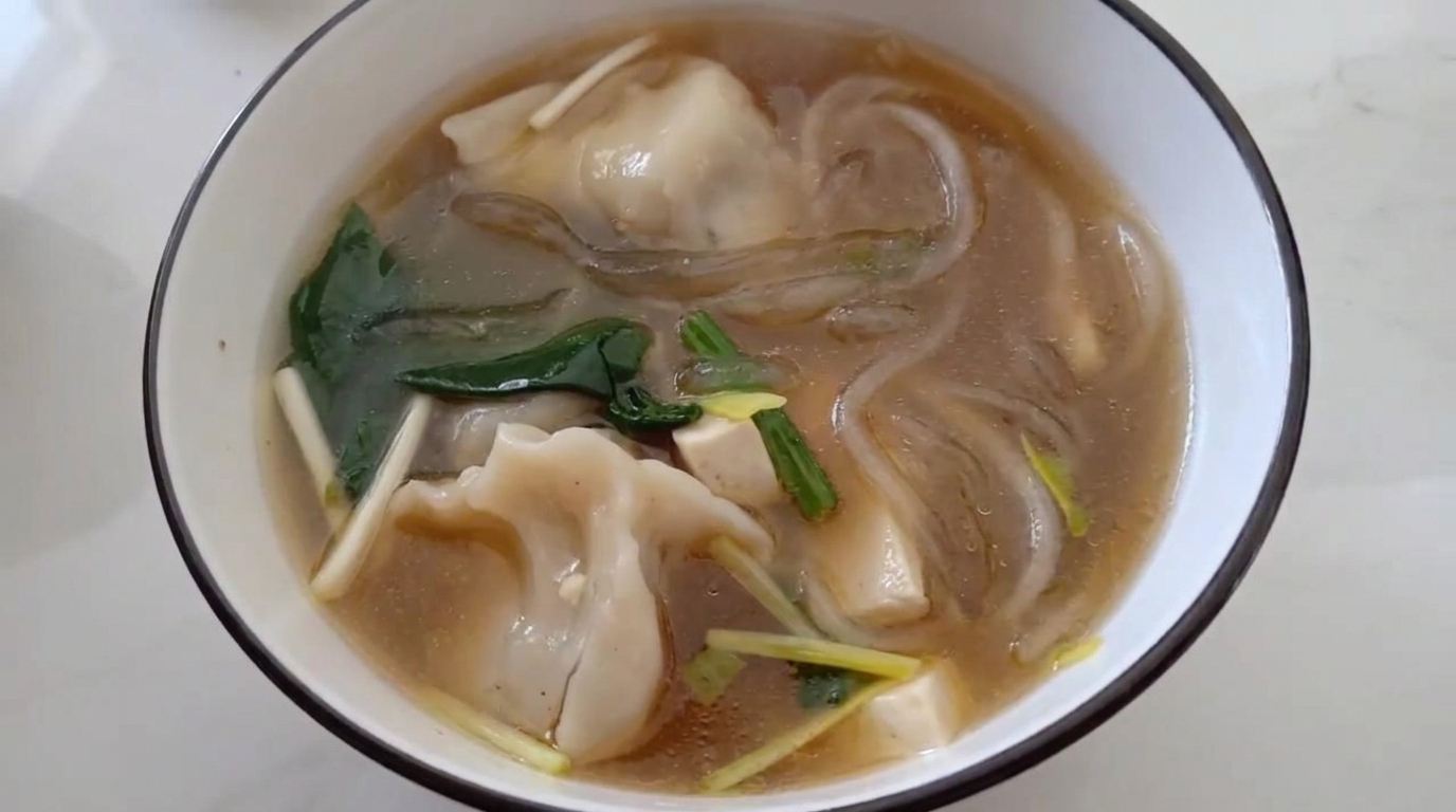 春雨、豆腐、新鮮なほうれん草が入った、旨味あふれる熱々の水餃子スープ。