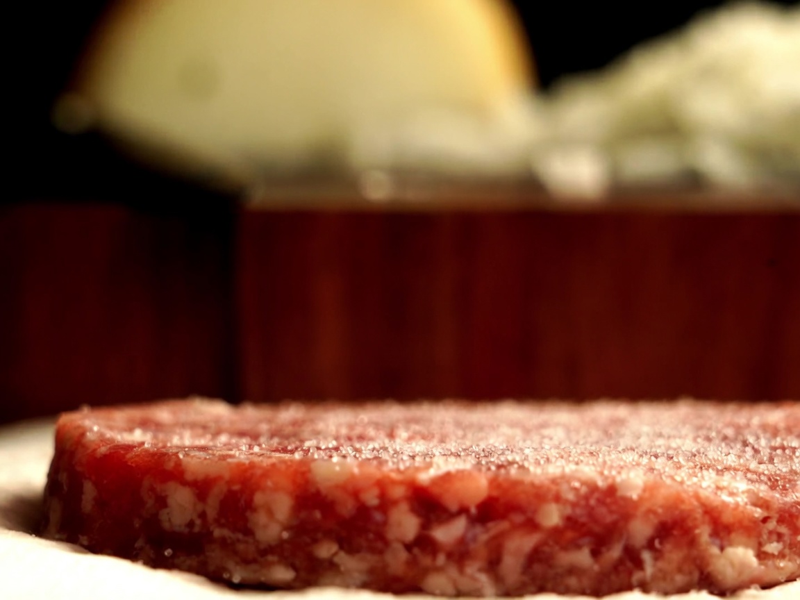 オーストラリア産和牛パティにミルで挽いた新鮮な黒胡椒をかけている様子。