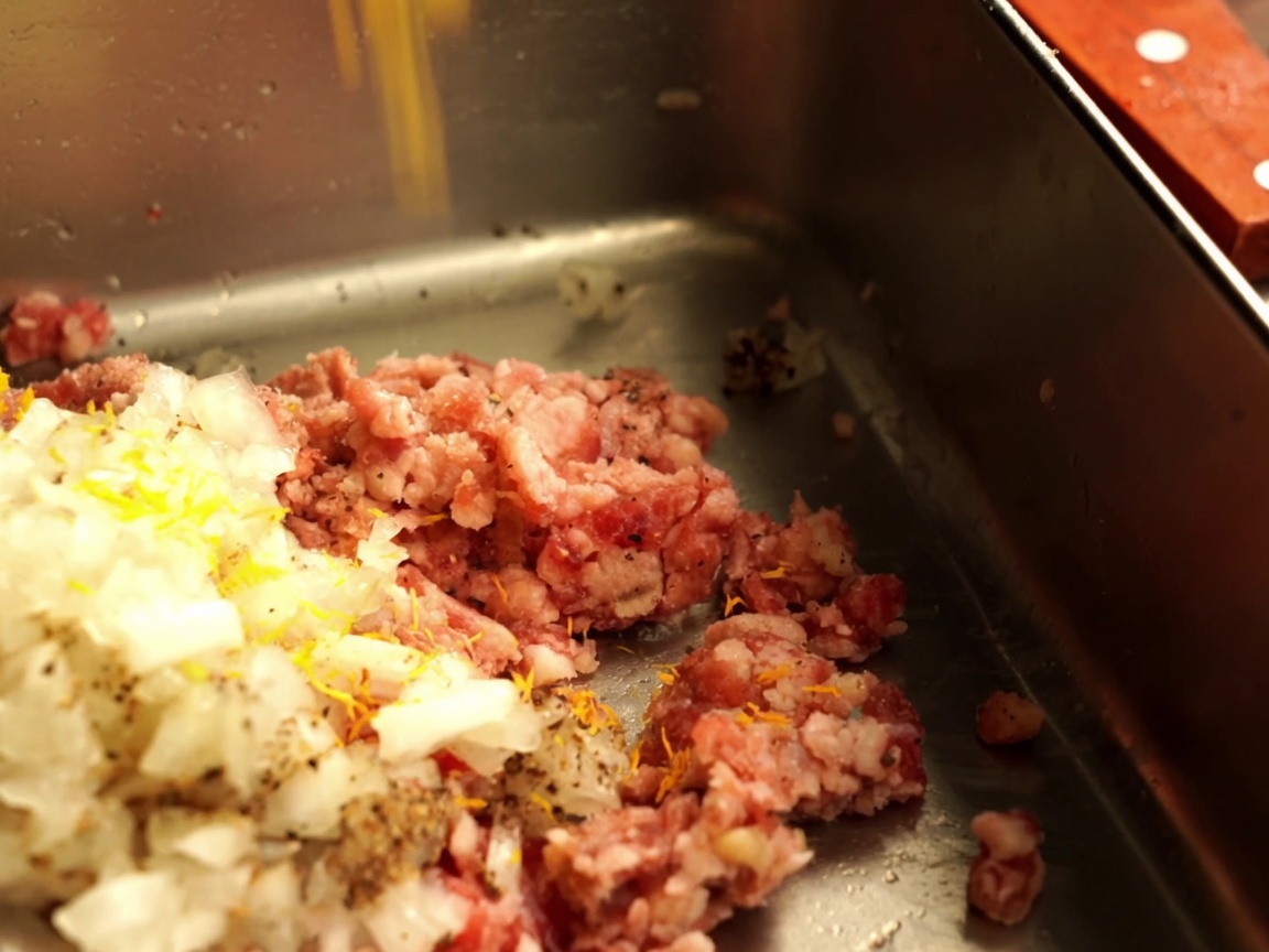 挽肉の中にみじん切りにした玉ねぎとパン粉を加えている様子。