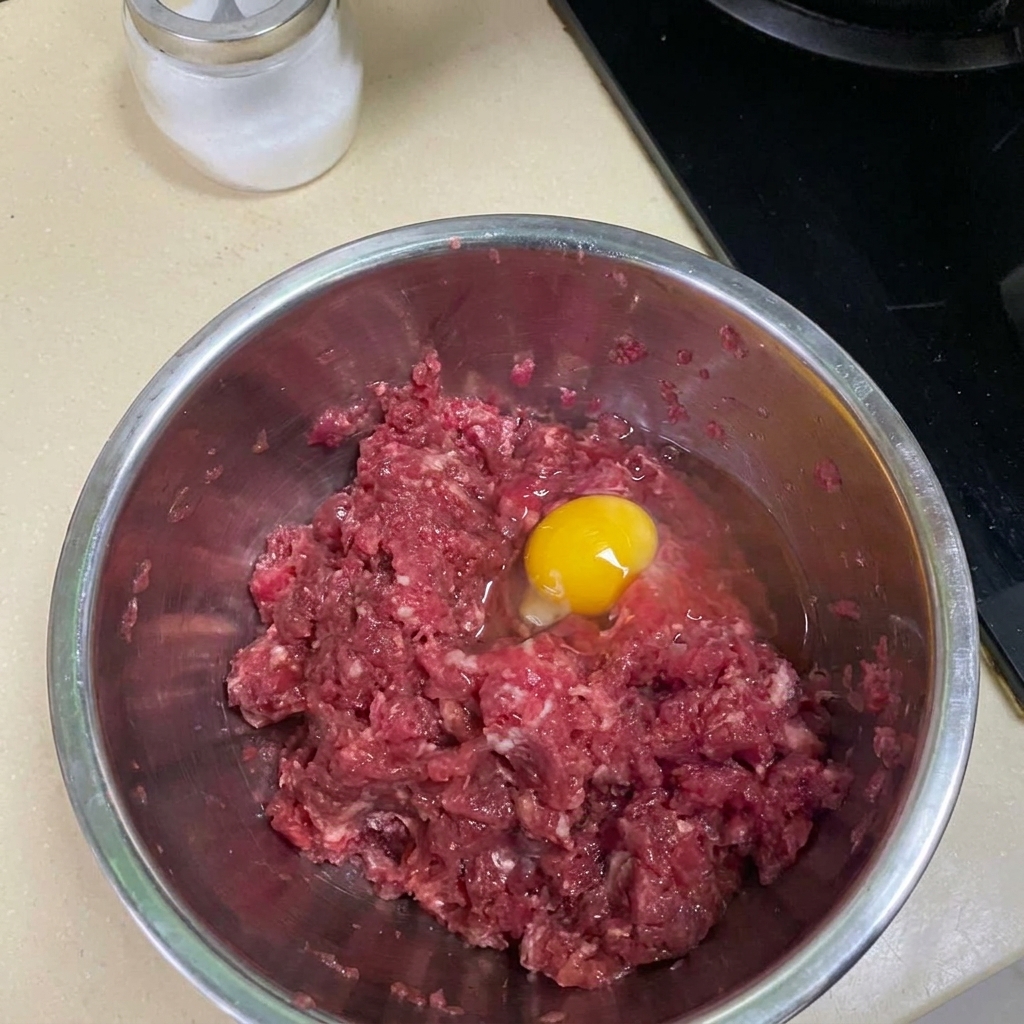 ボウルで牛肉とスパイス、卵を混ぜ合わせている様子。