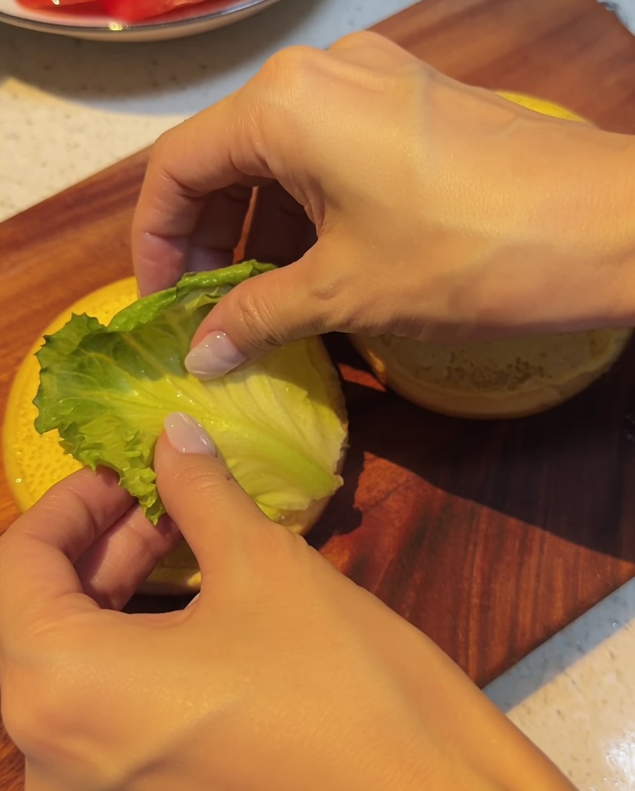 バンズの上に新鮮なレタスをのせている様子。
