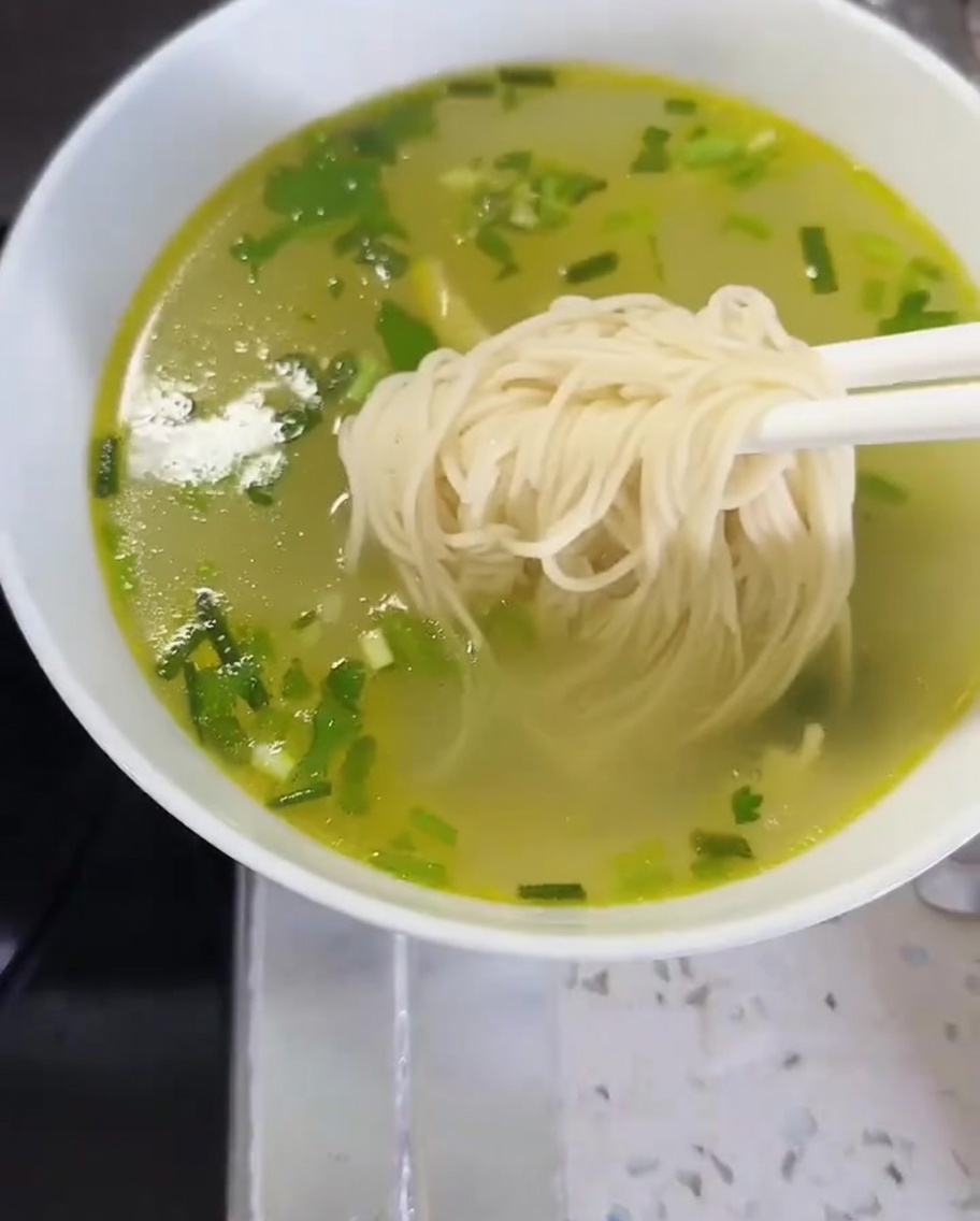 麺と野菜を器に盛り付けている様子。