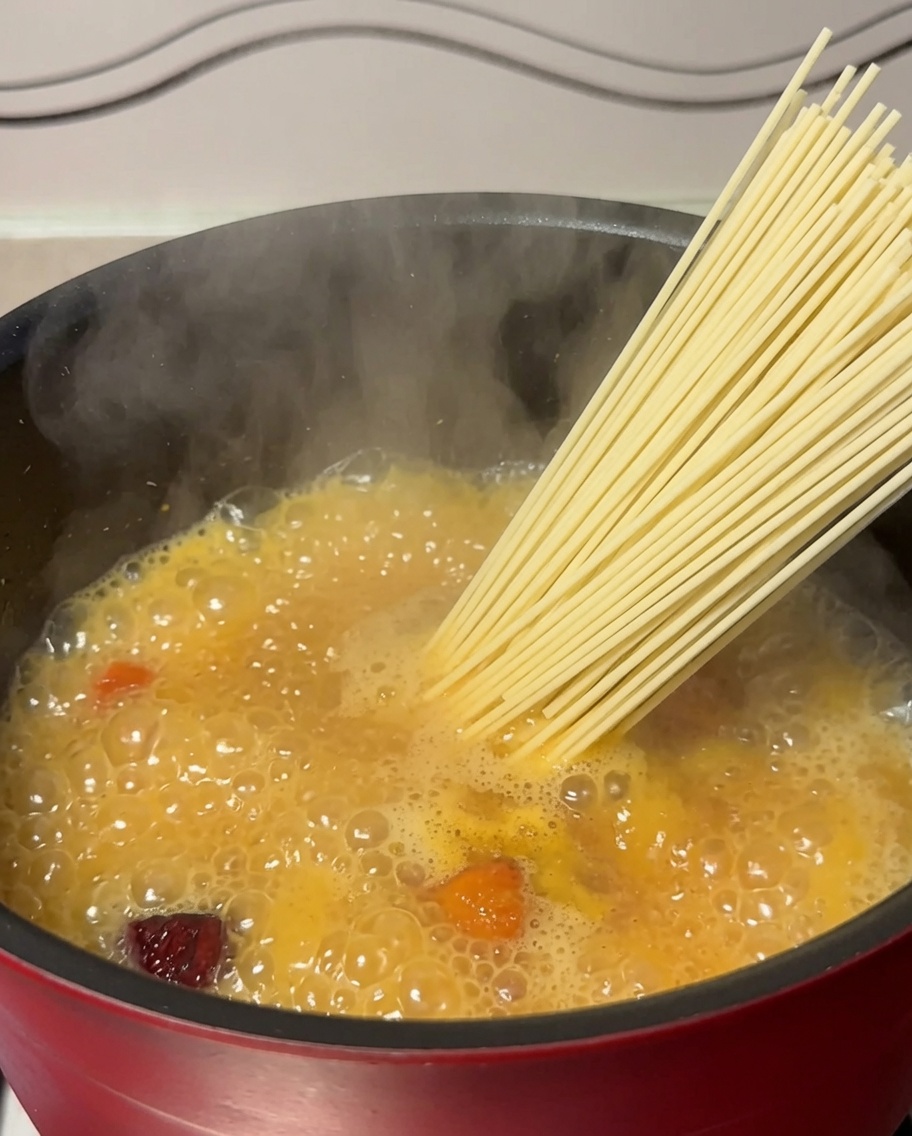 沸騰した鶏肉のスープの入った鍋に、乾麺を入れている様子。
