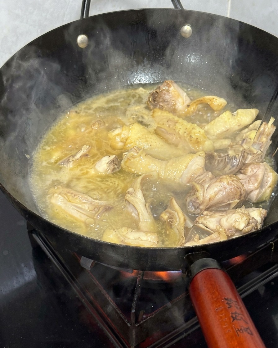 中華鍋の中で黄金色にグツグツと煮立つスープと鶏肉。