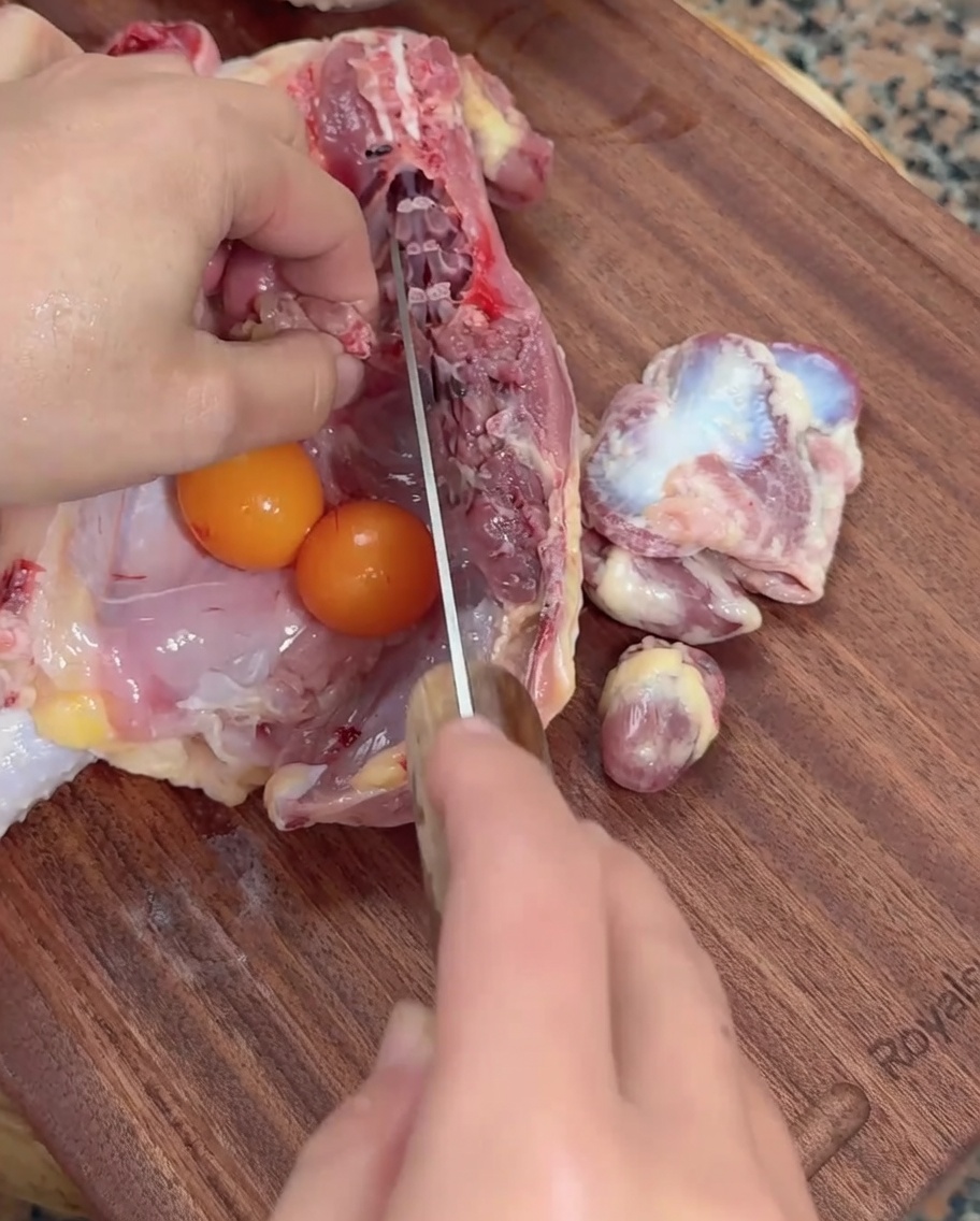 まな板の上で中華包丁を使い、鶏のホルモンを下処理している様子。