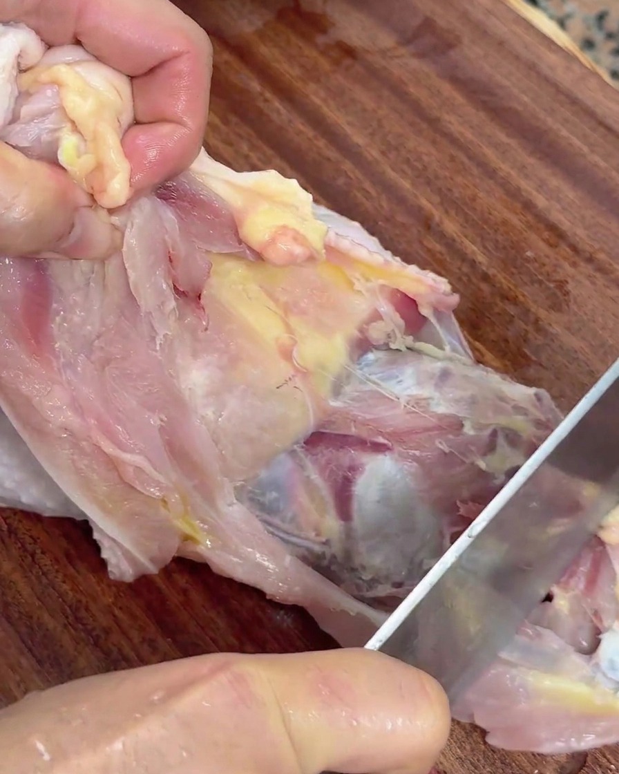 包丁で鶏肉を骨から丁寧に外している様子。