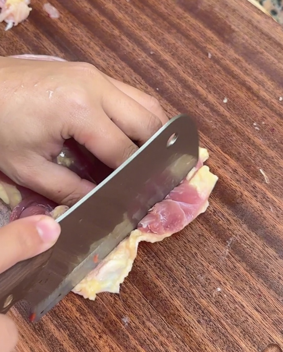 まな板の上で鶏肉を薄くスライスしている様子。