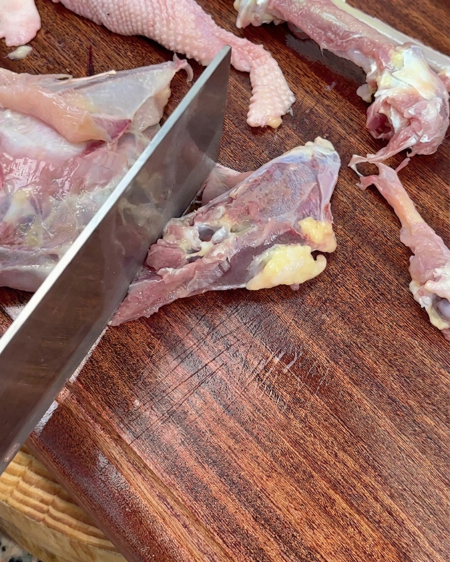 中華包丁で鶏ガラを大きくぶつ切りにしている様子。