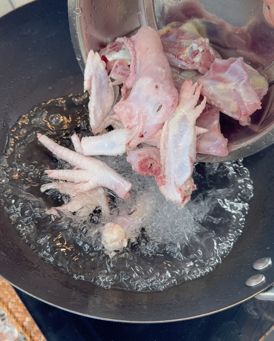 沸騰したお湯に鶏ガラと足を入れている様子。