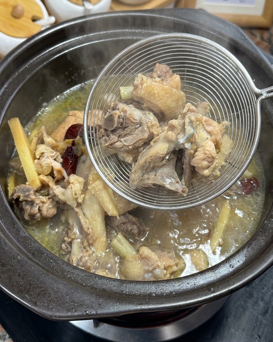 金網で骨とハーブをスープから取り出している様子。