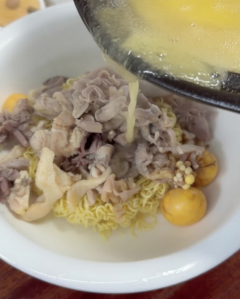 熱々の黄金スープを麺の上から注いでいる様子。