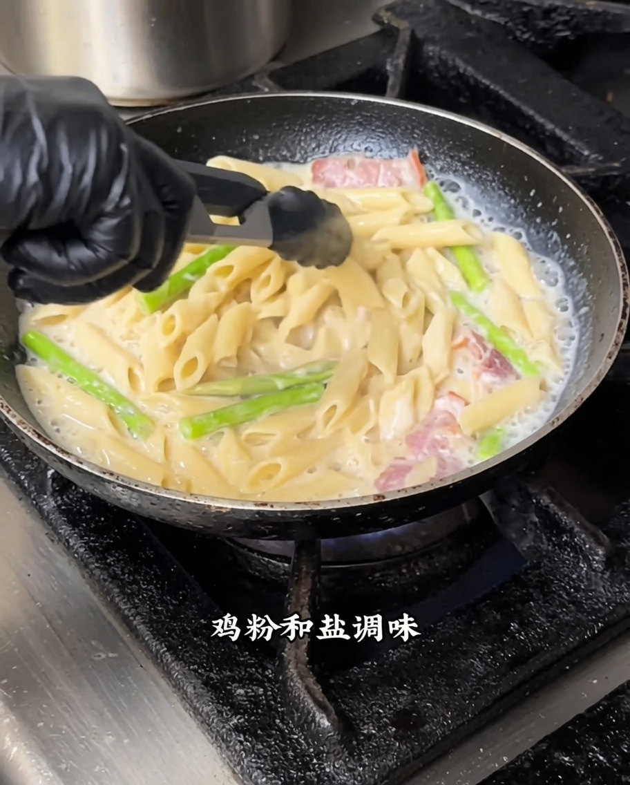 中火でホワイトソースと黒トリュフをペンネに混ぜ込んでいる様子。