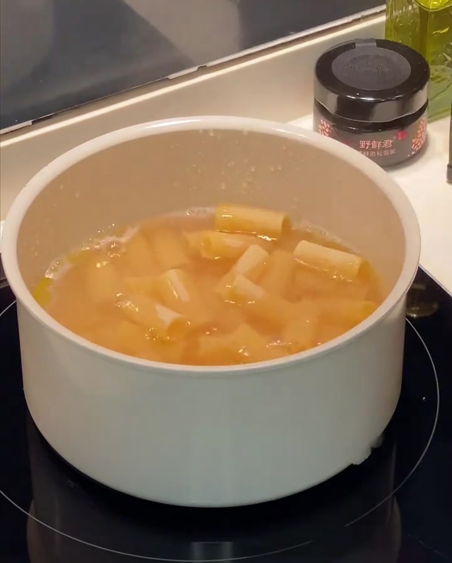 鍋で茹でられているリガトーニ。表面に油のしずくが浮かんでいる。