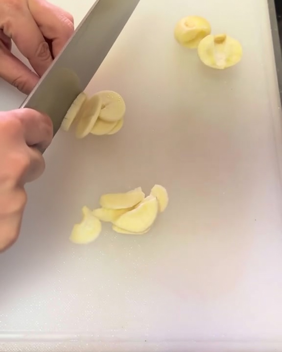 白いまな板の上に薄切りにされたにんにく。