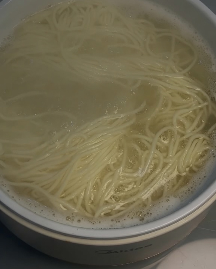 ザルを使って茹でた麺を引き上げる様子。