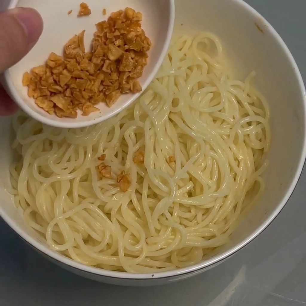 麺の上にカリカリの揚げニンニクを振りかける様子。