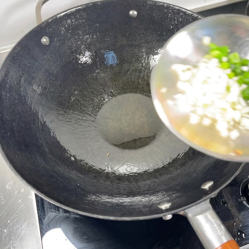 熱した中華鍋の油に、刻んだ青ねぎとみじん切りにしたにんにくを入れているところ。