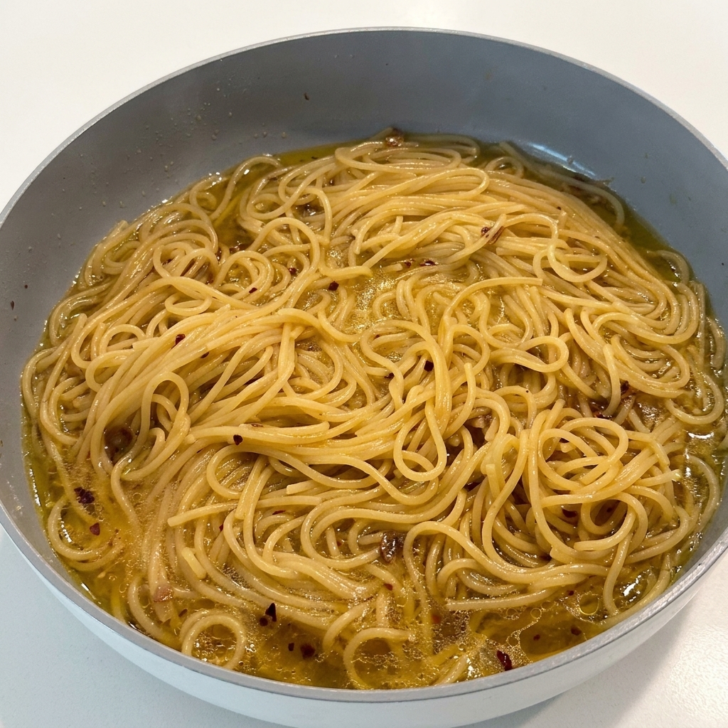 調理中のパスタに黒こしょうを振りかけている様子