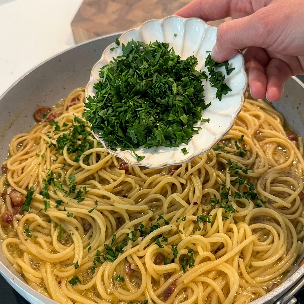 完成したパスタに刻んだフレッシュパセリを散らしている様子