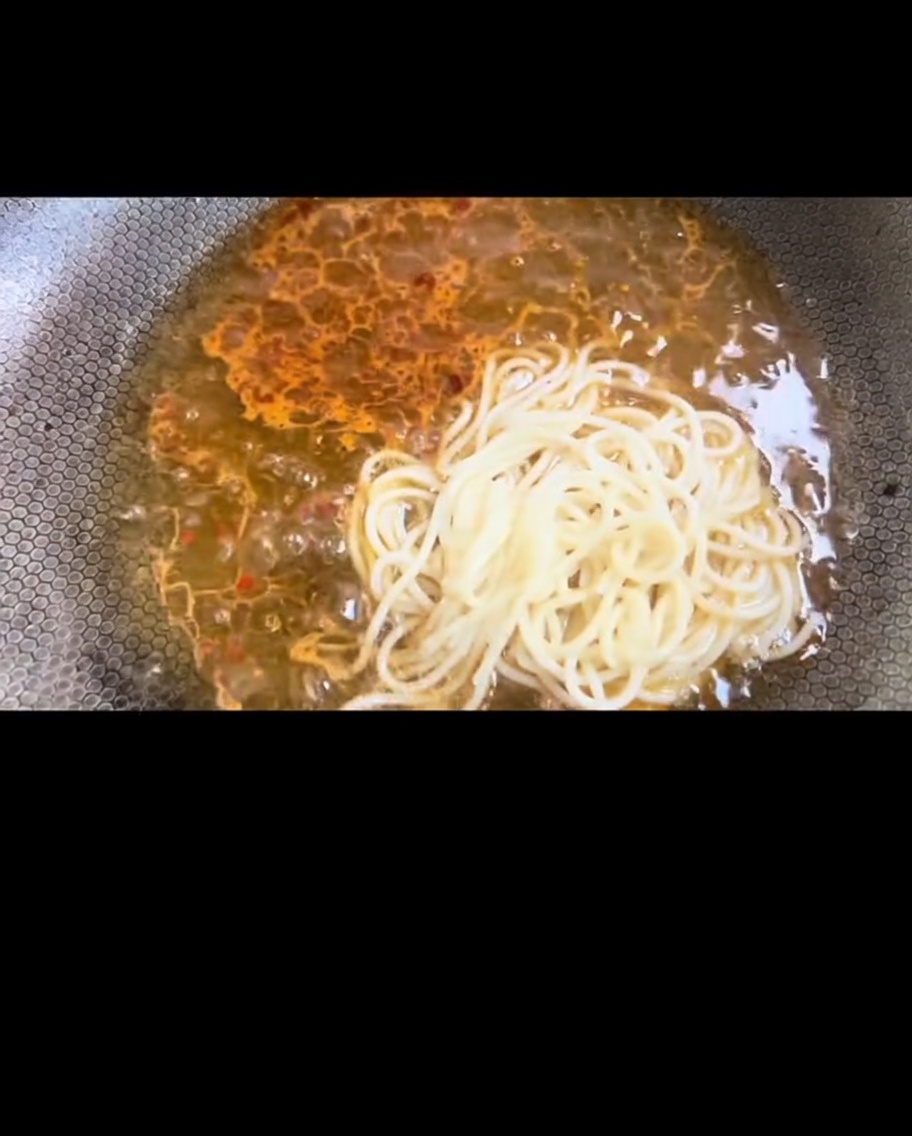 ゆで上がったパスタをフライパンに移し、ソースと絡めている様子。