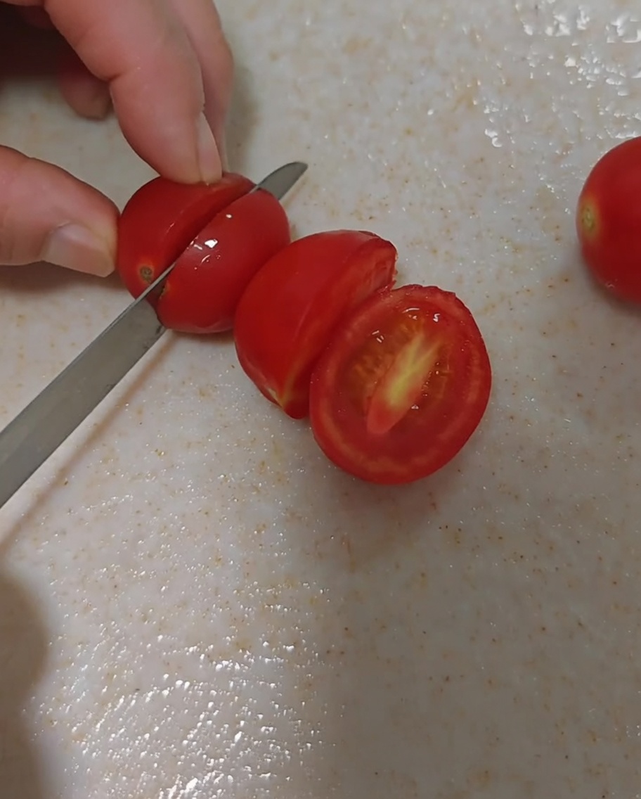 まな板の上で丁寧に半分に切られた新鮮なミニトマト。