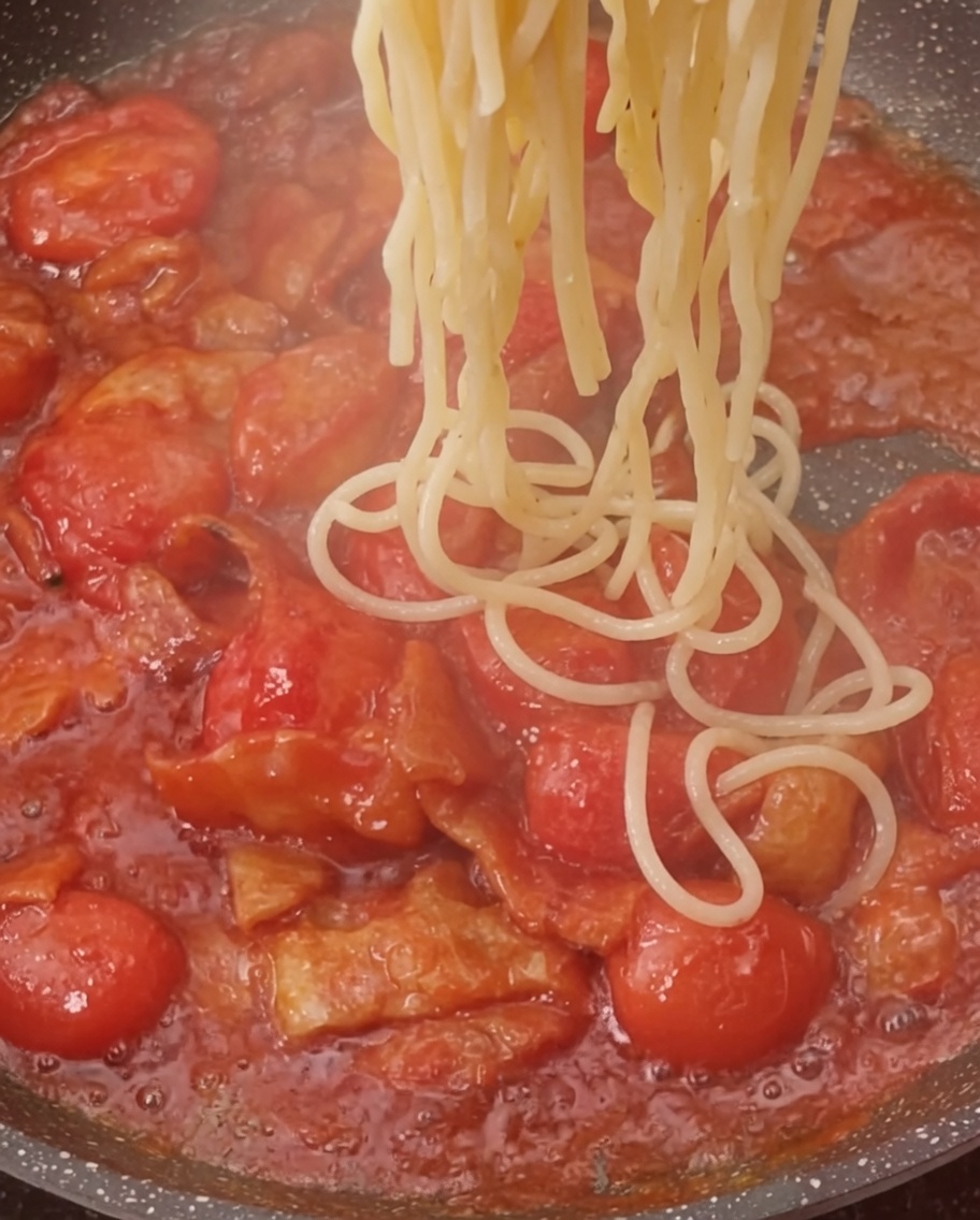 茹でたパスタをソースの入ったフライパンに加える様子。