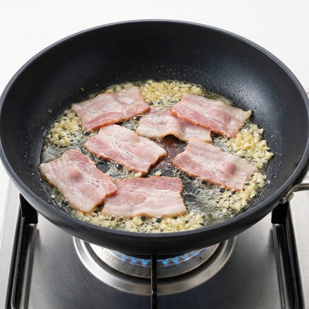 フライパンで焼かれるベーコンとニンニク。