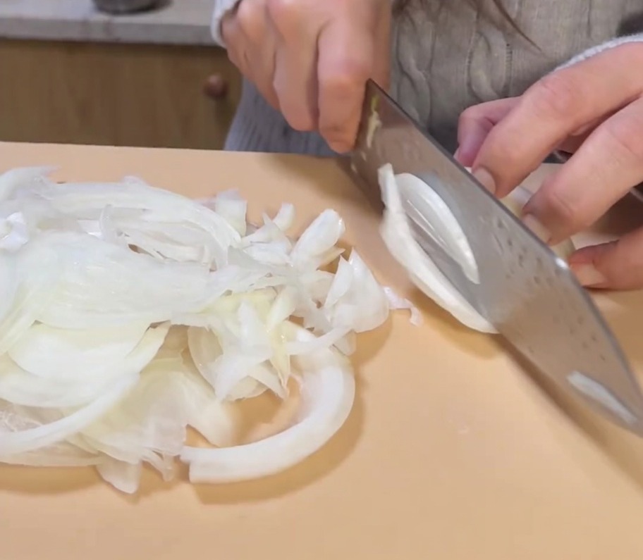 まな板の上で玉ねぎを薄くスライスしている様子。